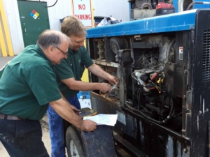 two OSC team members working on a machine together