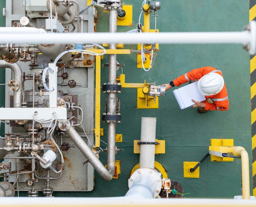 an overhead shot of a worker with a hard hat reading a pressure valve