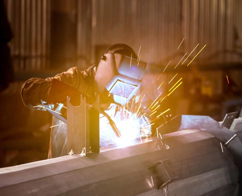 a masked industrial welder welds a metal structure