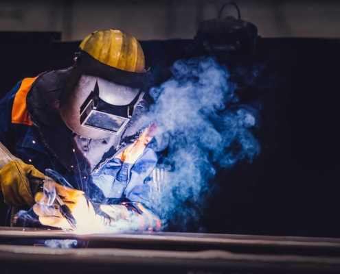 engineer in welding mask using a welding tool